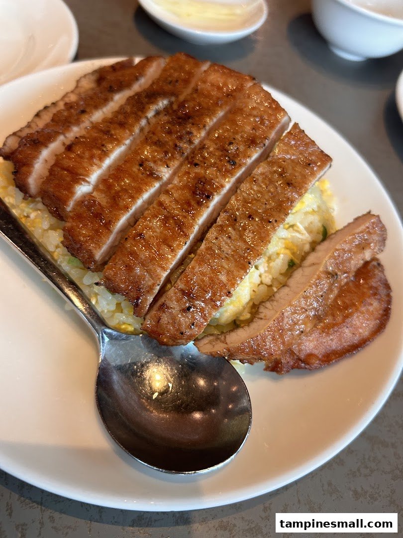 A close-up of Din Tai Fung's signature pork chop fried rice on a white plate.