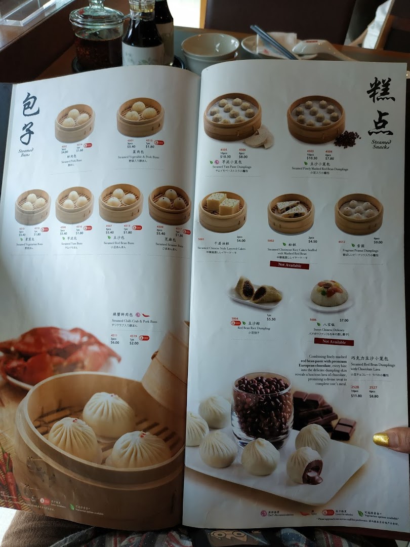 A detailed menu from Din Tai Fung, showcasing a variety of steamed buns and snacks with prices and descriptions.