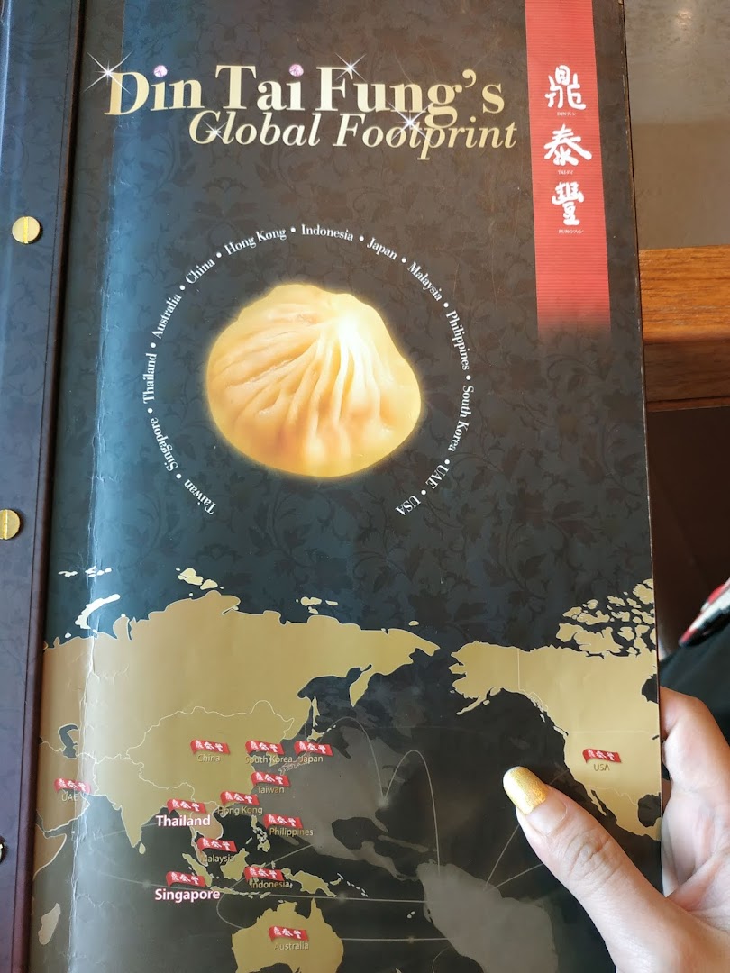The cover of a Din Tai Fung booklet showcasing its global presence with a map and signature xiao long bao.