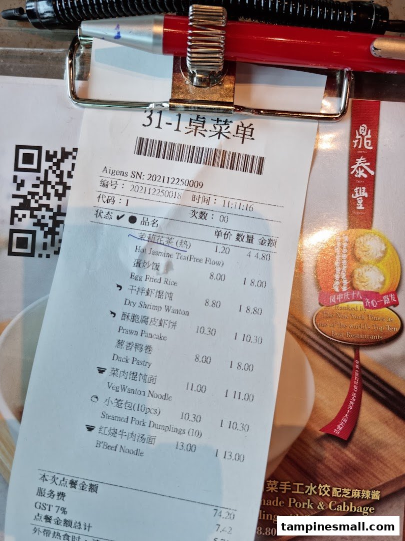 A close-up of a Din Tai Fung order slip/menu with a pen, showing various food items and prices.