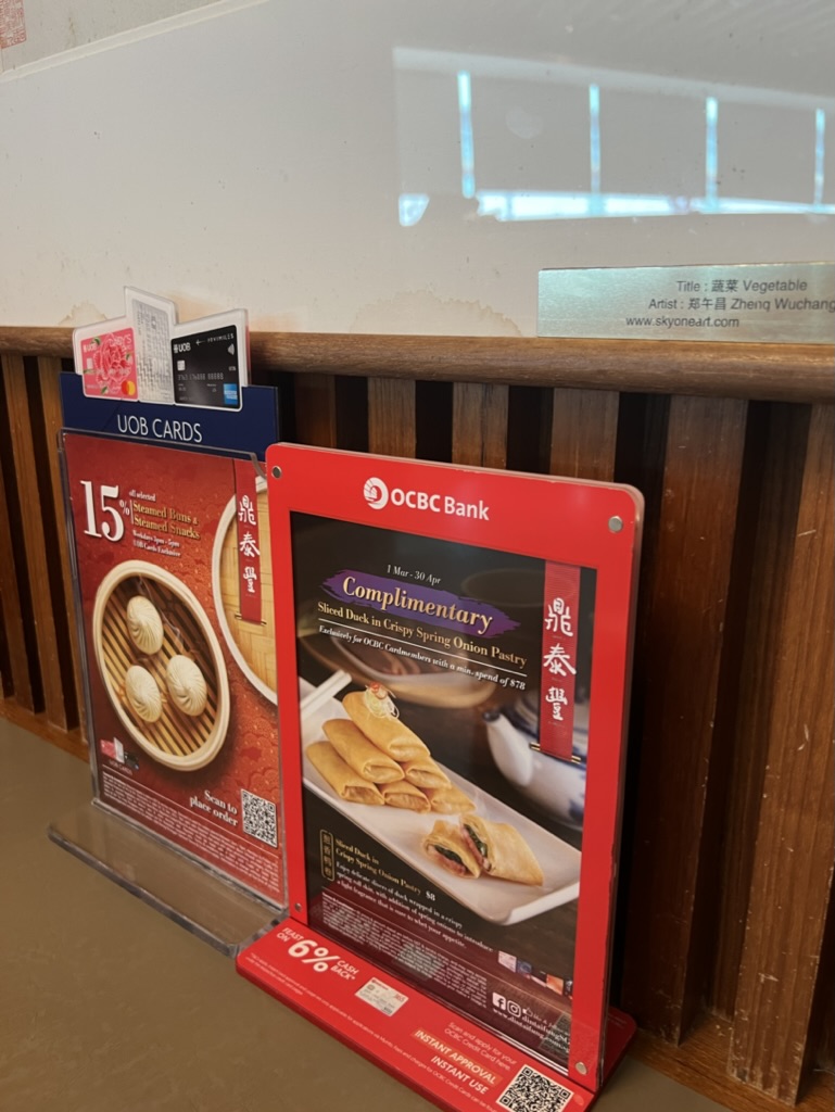 Promotional stands at Din Tai Fung featuring bank card offers and a QR code for ordering.