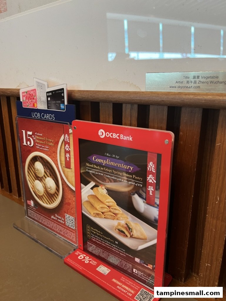 Promotional stands at Din Tai Fung featuring bank card offers and a QR code for ordering.