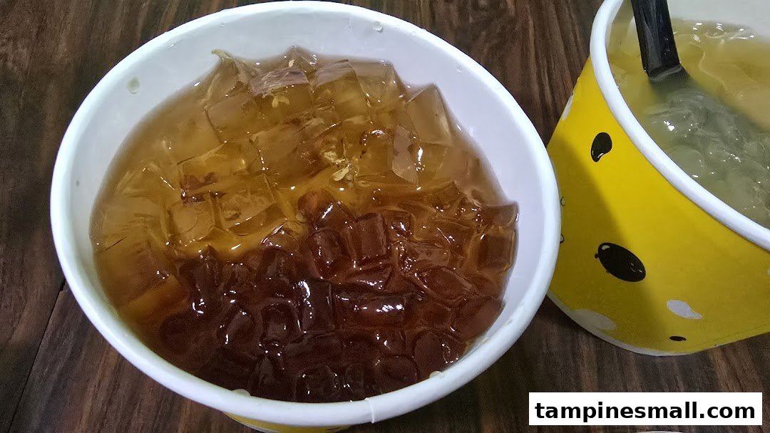 Two cups of refreshing jelly desserts, one prominently featuring amber and dark brown jelly cubes.