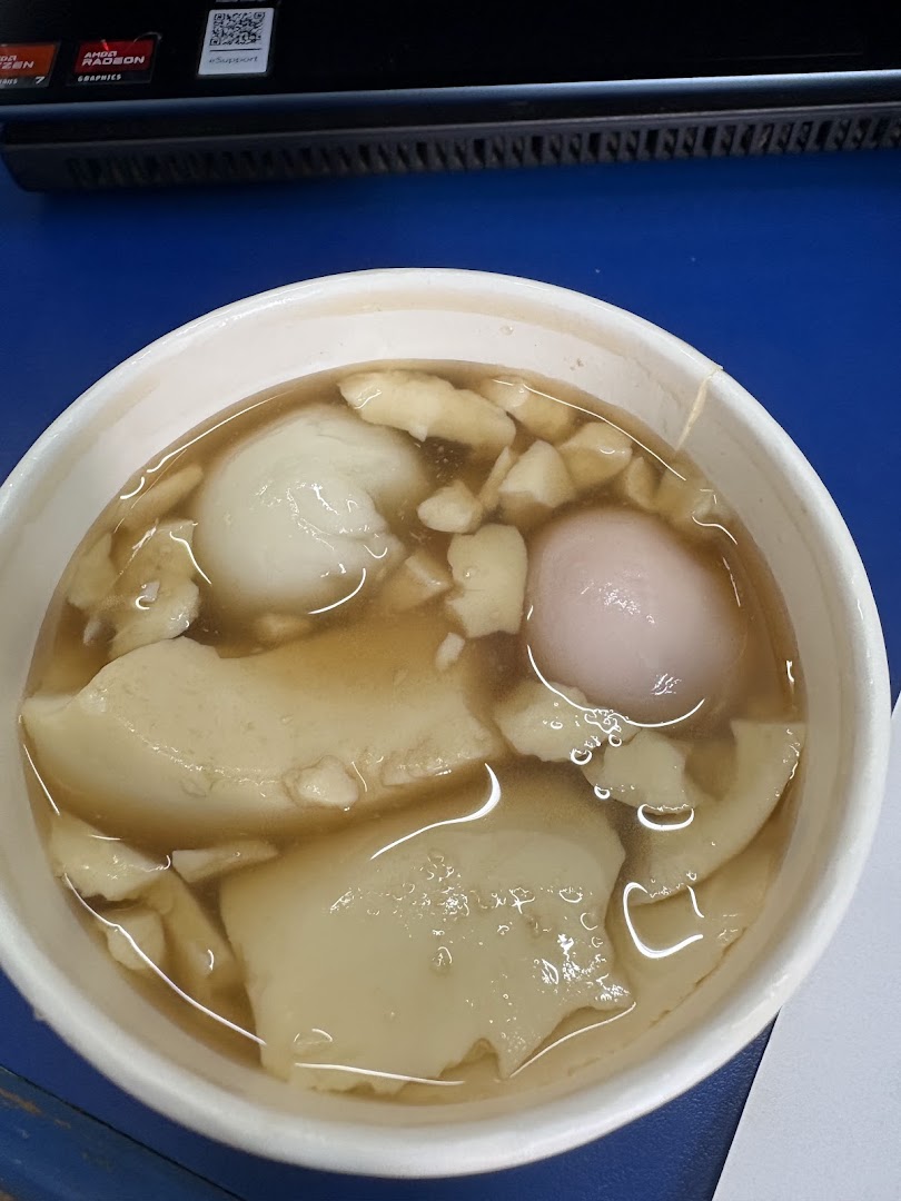 A close-up of a bowl of traditional tofu pudding dessert with glutinous rice balls.