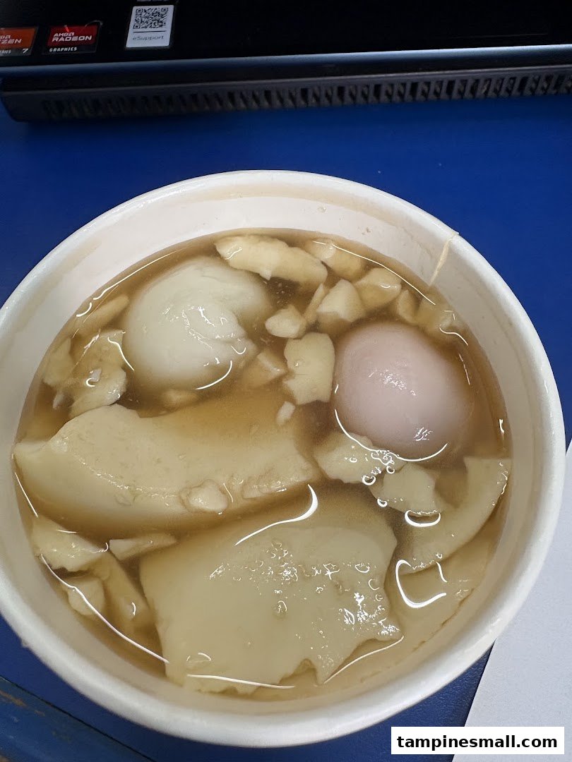 A close-up of a bowl of traditional tofu pudding dessert with glutinous rice balls.
