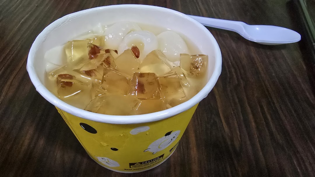 A refreshing dessert cup filled with jelly, longans, and goji berries, served with a spoon.