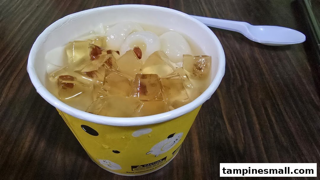 A refreshing dessert cup filled with jelly, longans, and goji berries, served with a spoon.