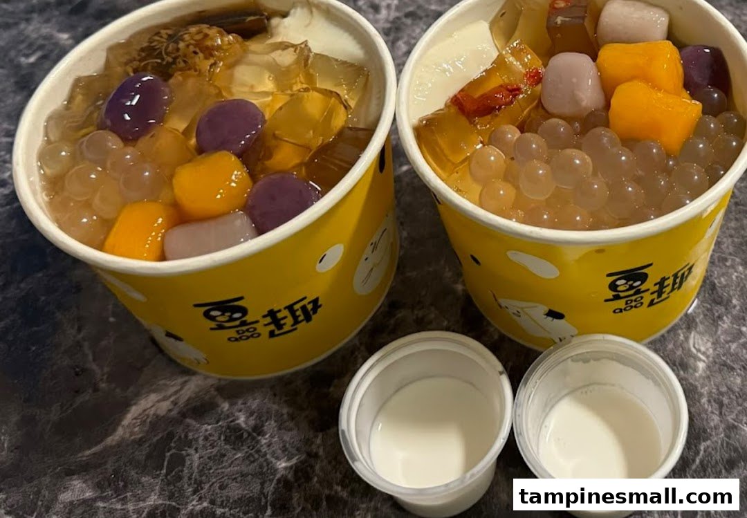 Two vibrant dessert cups from Do Qoo, filled with colorful toppings, jellies, and pearls, alongside two small milk cups.