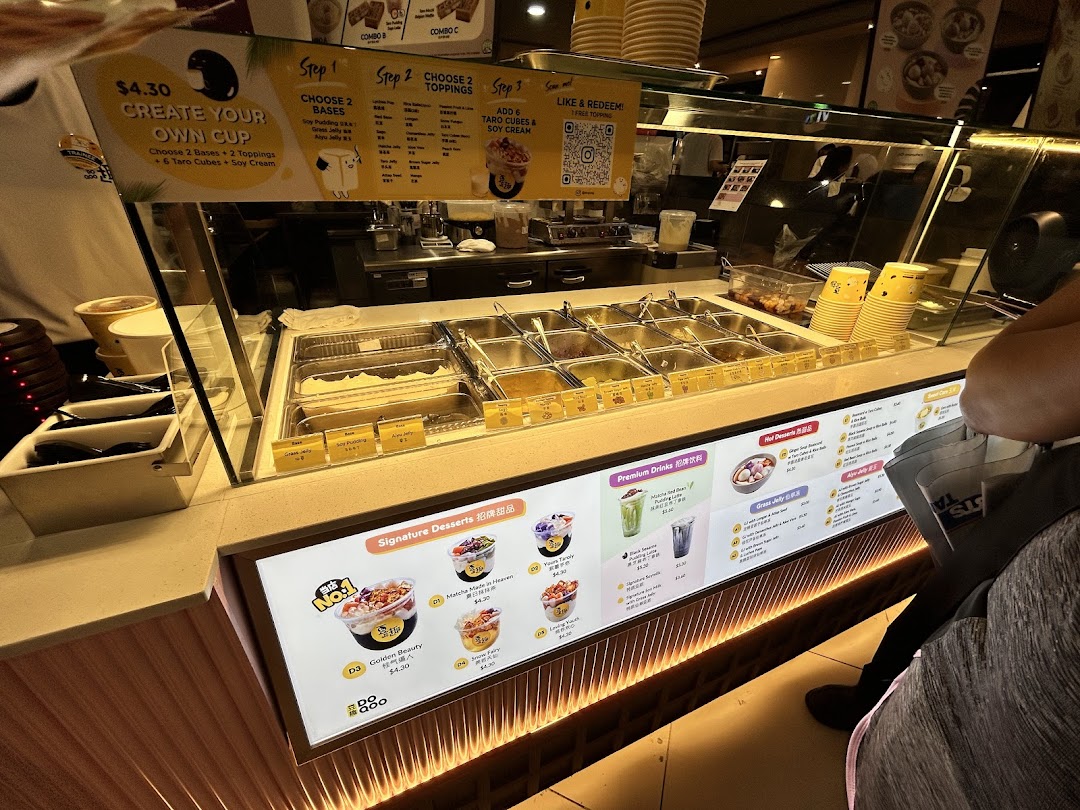 A vibrant counter at Do Qoo 豆趣 showcasing fresh ingredients and digital menu displays.