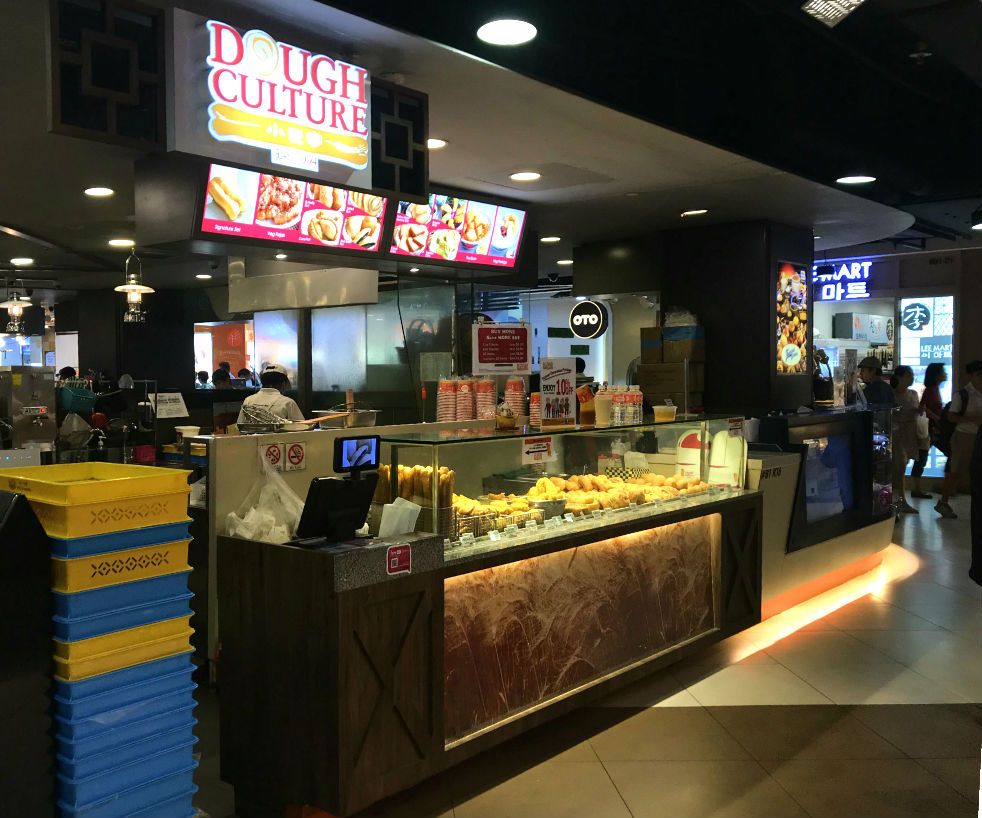 Dough Culture's counter displaying freshly baked dough products and digital menu boards.