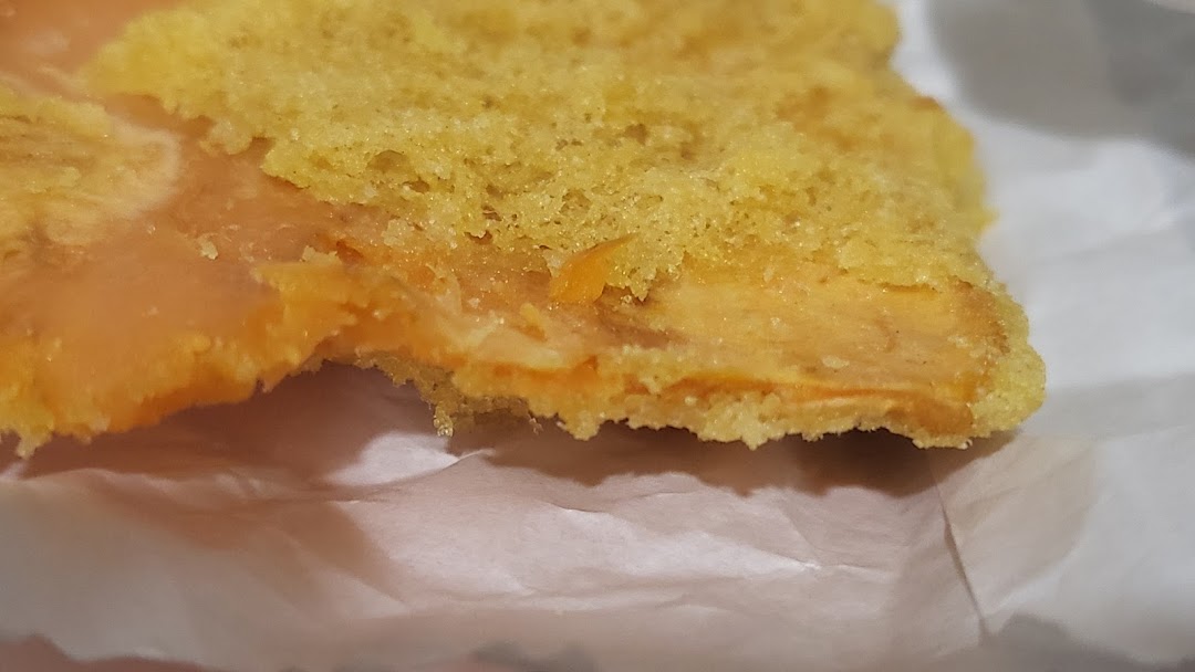 Close-up of a delicious-looking pastry with a golden-yellow top and a creamy orange filling.