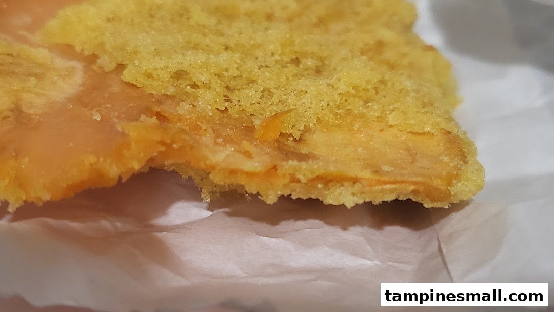 Close-up of a delicious-looking pastry with a golden-yellow top and a creamy orange filling.