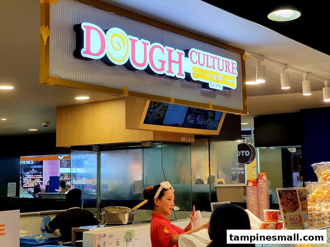 The bustling counter of Dough Culture, featuring staff, fresh products, and the shop's illuminated sign.