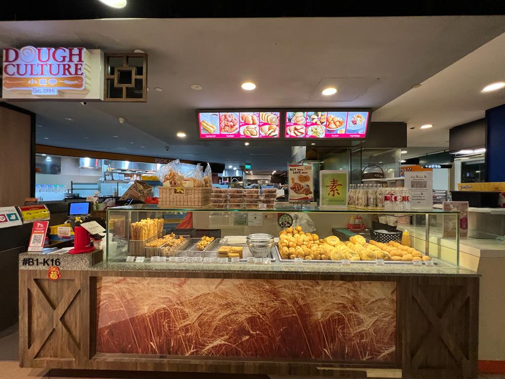 A vibrant display counter at Dough Culture, showcasing a variety of freshly prepared fried dough snacks and pastries.