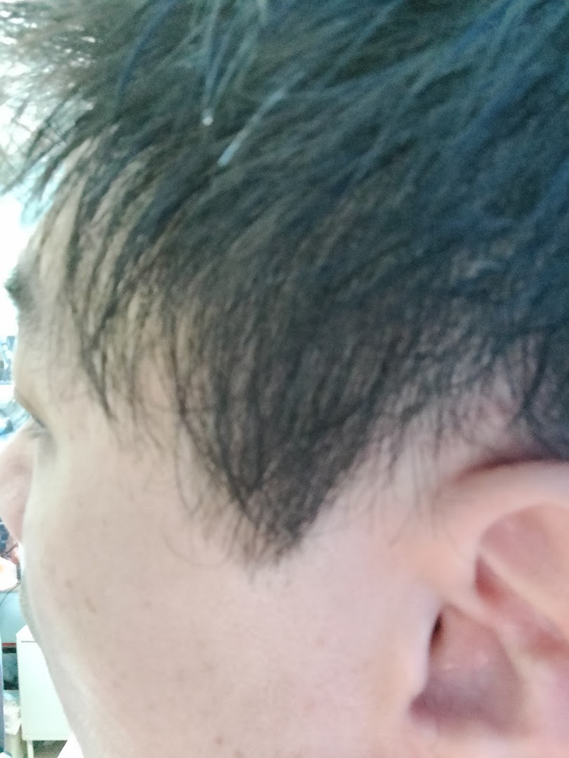 A close-up view of a person's head, showing dark hair and the side of an ear, likely after a haircut.