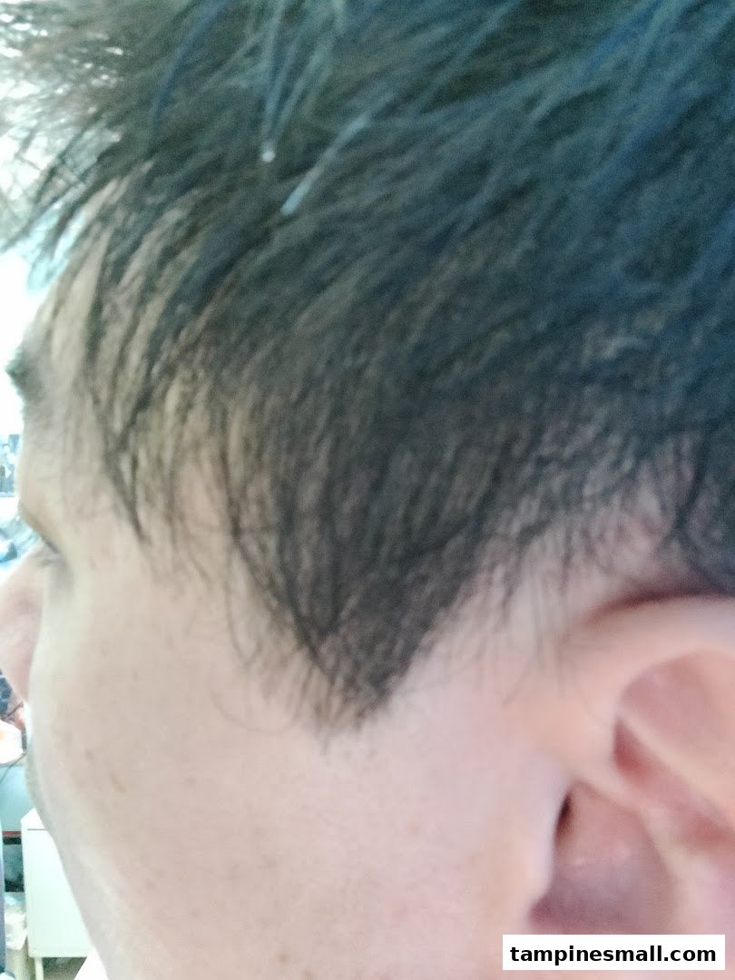 A close-up view of a person's head, showing dark hair and the side of an ear, likely after a haircut.