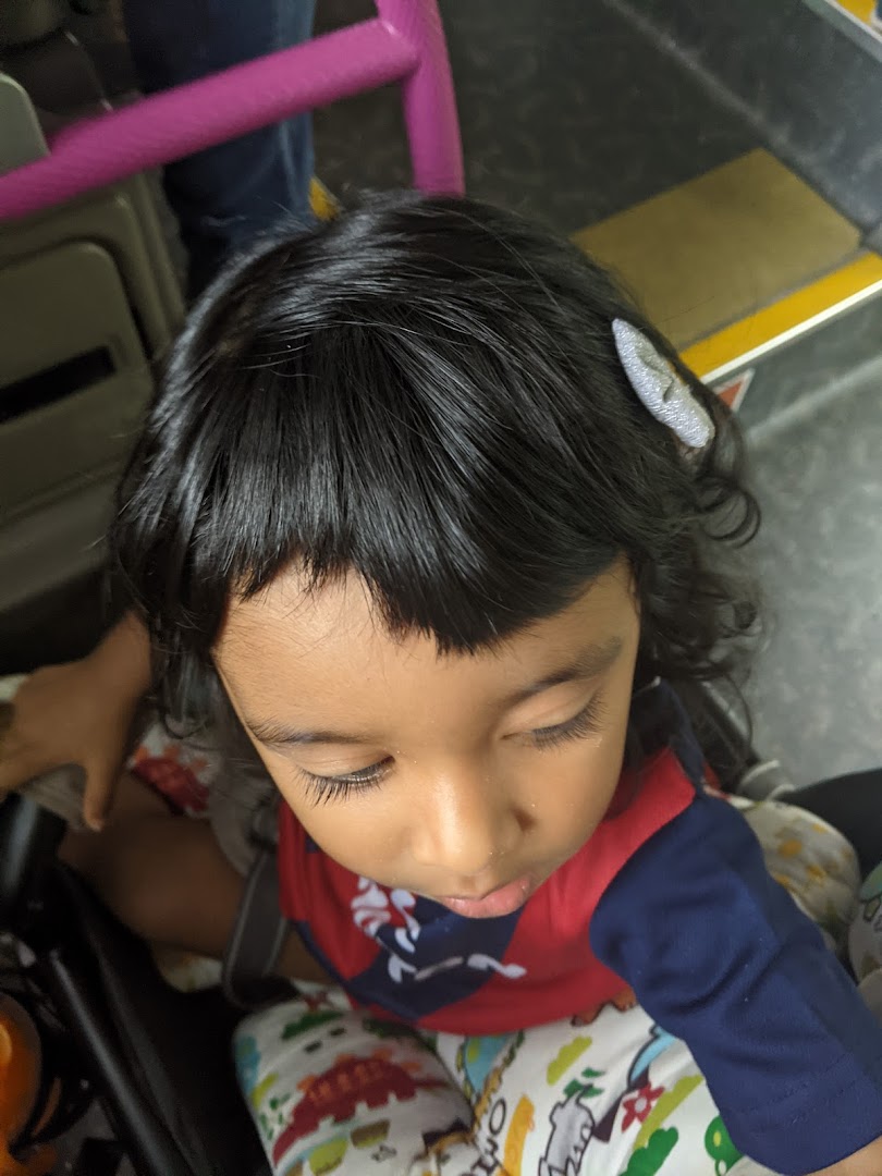 A close-up overhead shot of a child with dark hair and a hair clip, looking down.