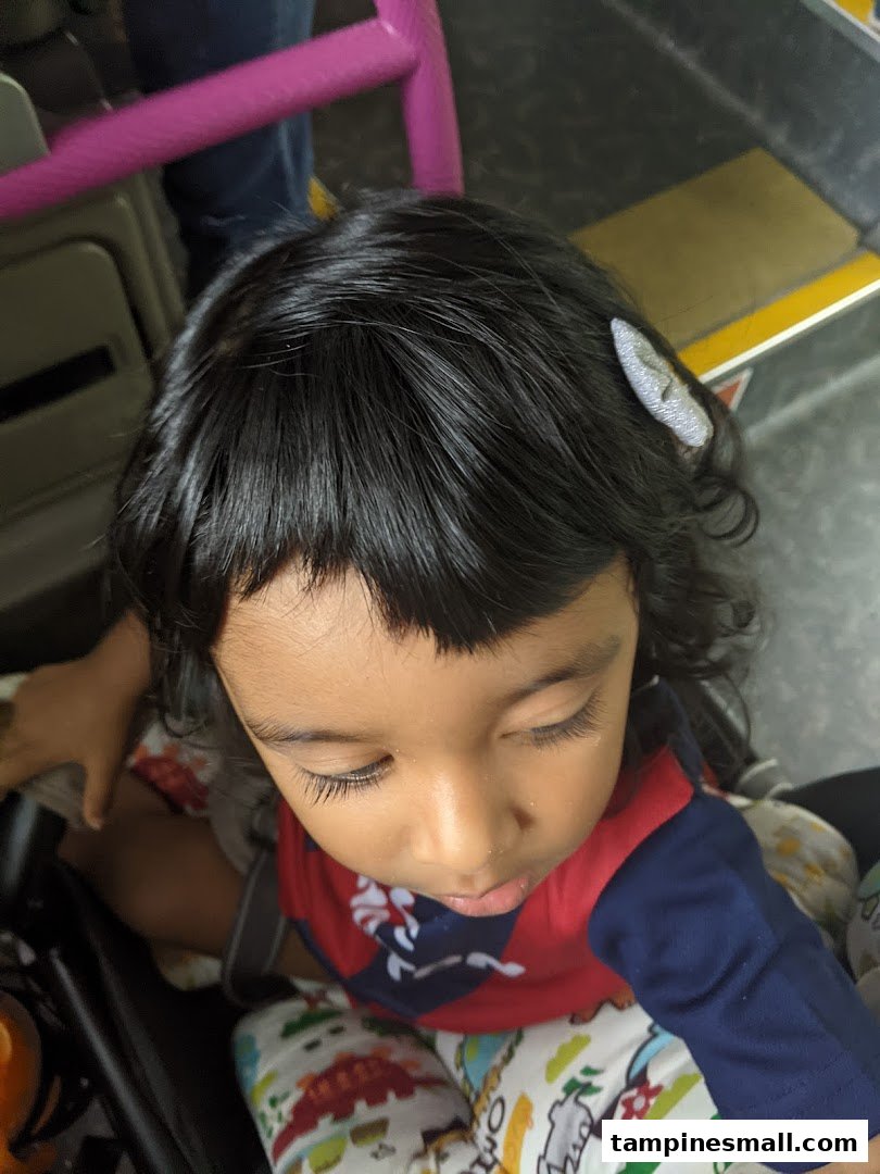 A close-up overhead shot of a child with dark hair and a hair clip, looking down.