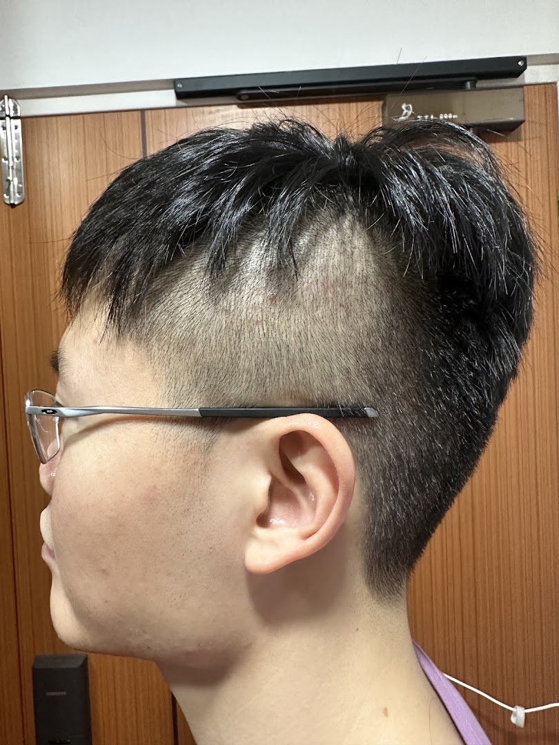 Side profile of a person showcasing a fresh haircut with a stylish faded undercut.