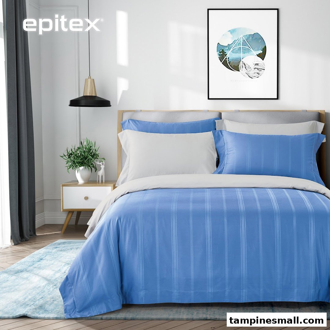 A modern bedroom featuring blue and white striped bedding, a bedside table, and a hanging lamp.