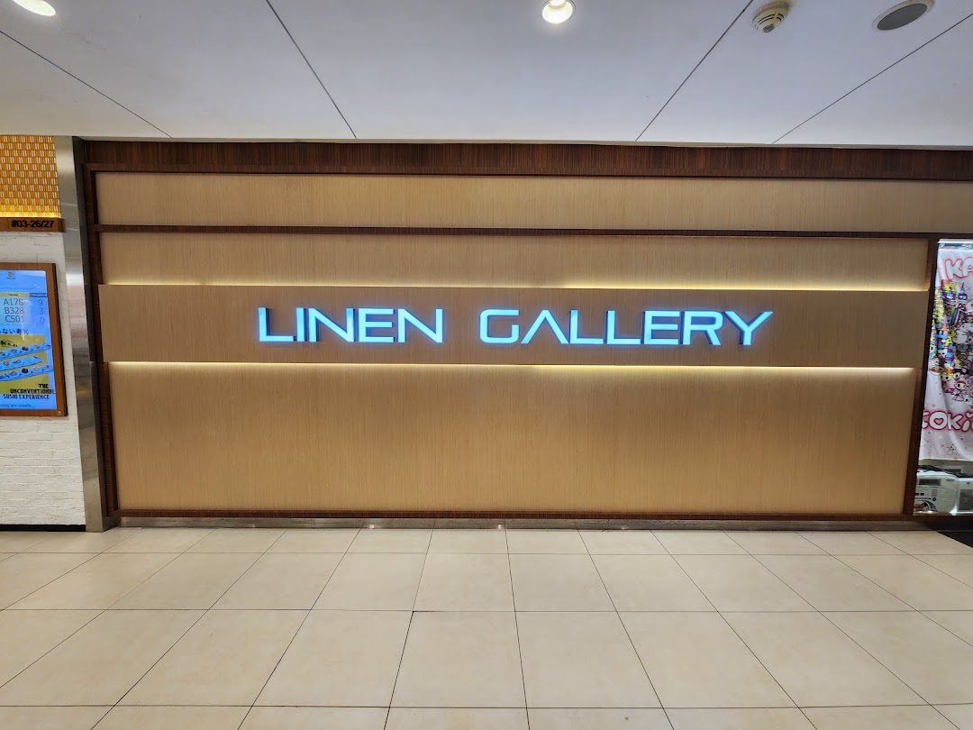 Illuminated 'LINEN GALLERY' signage on a textured wall inside a shopping mall.