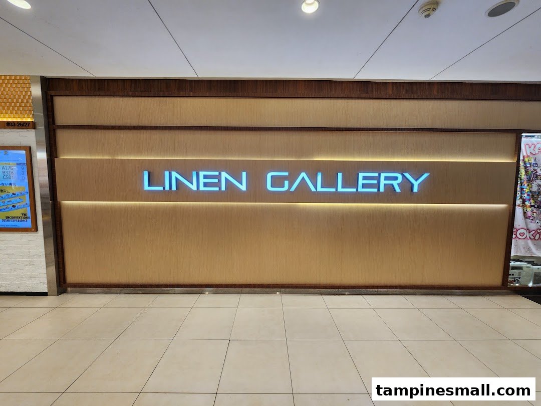 Illuminated 'LINEN GALLERY' signage on a textured wall inside a shopping mall.