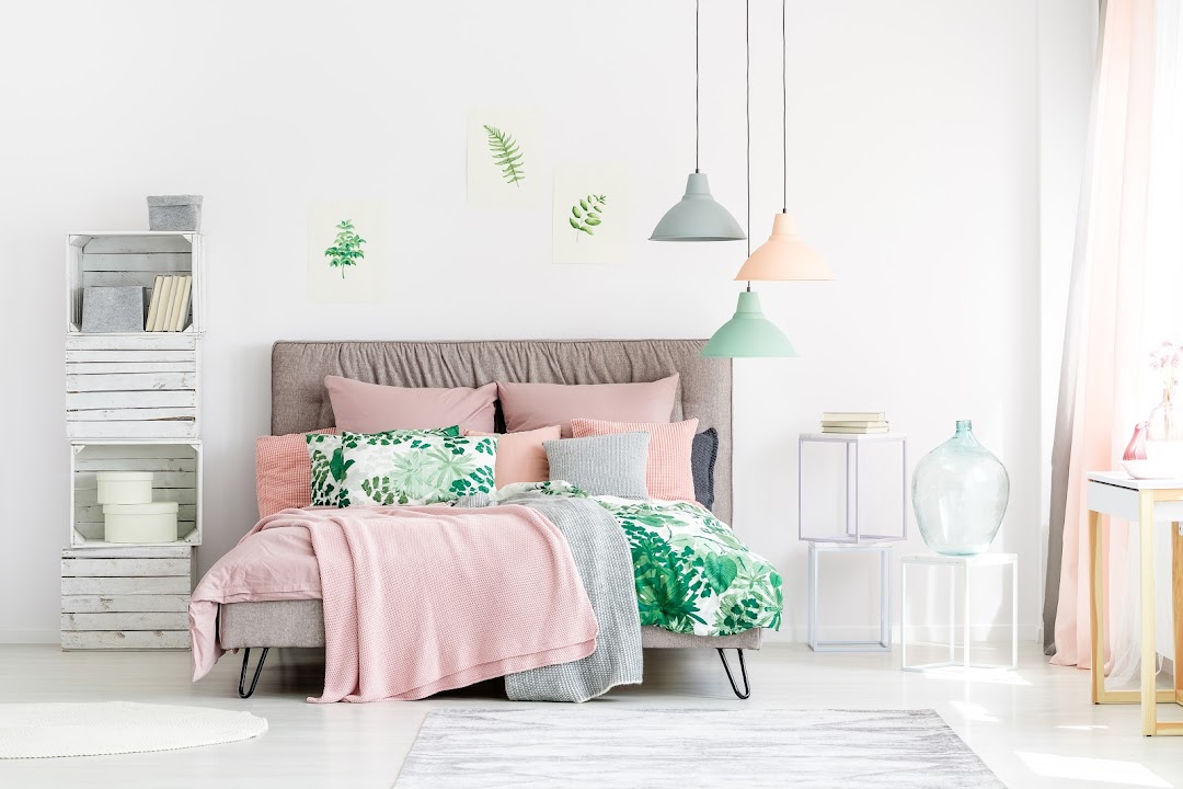 A beautifully styled bedroom featuring soft pink and green bedding, decorative pillows, and modern home decor.