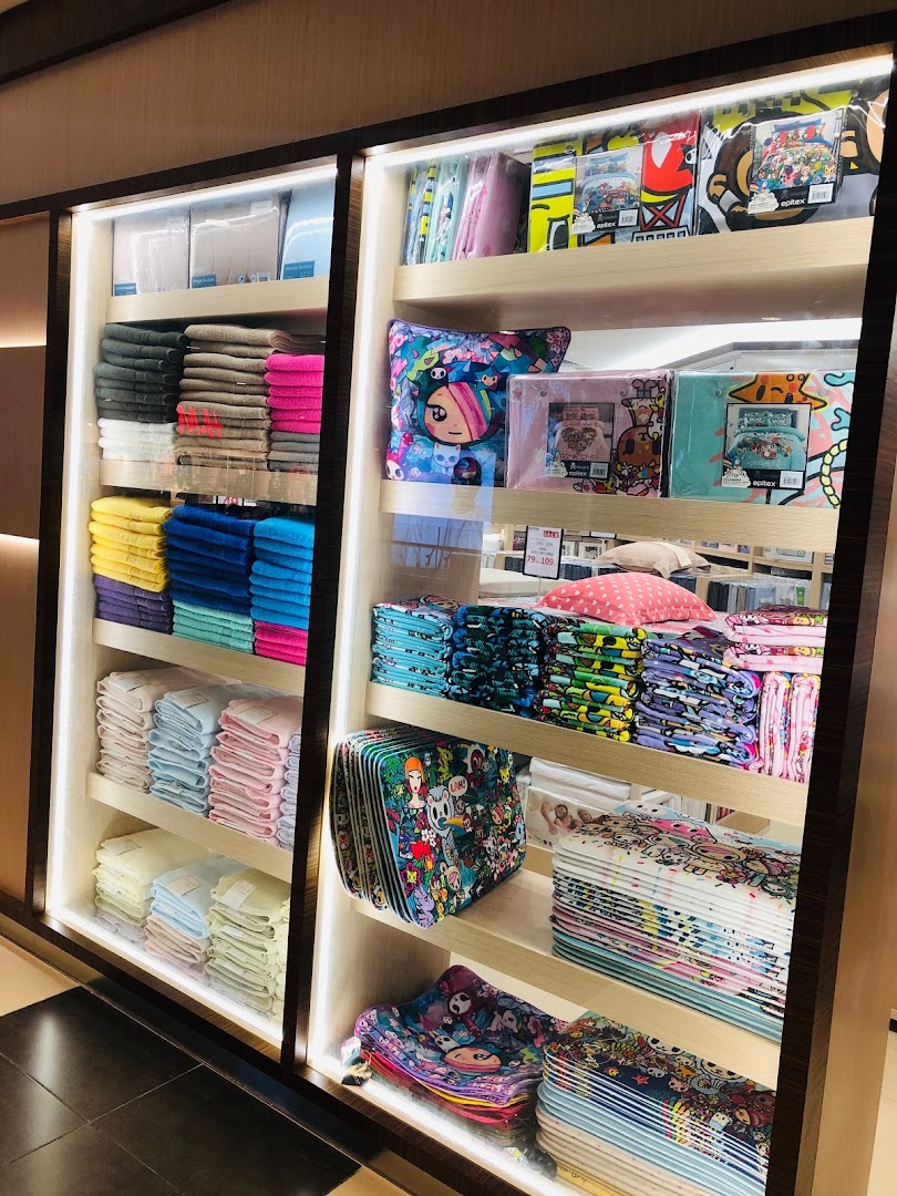 Shelves displaying a vibrant collection of Epitex home textiles, including towels and character-themed bedding.