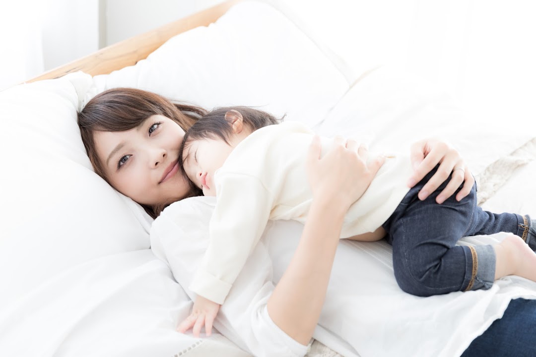 A woman and child comfortably resting on a bed, showcasing soft and inviting bedding.