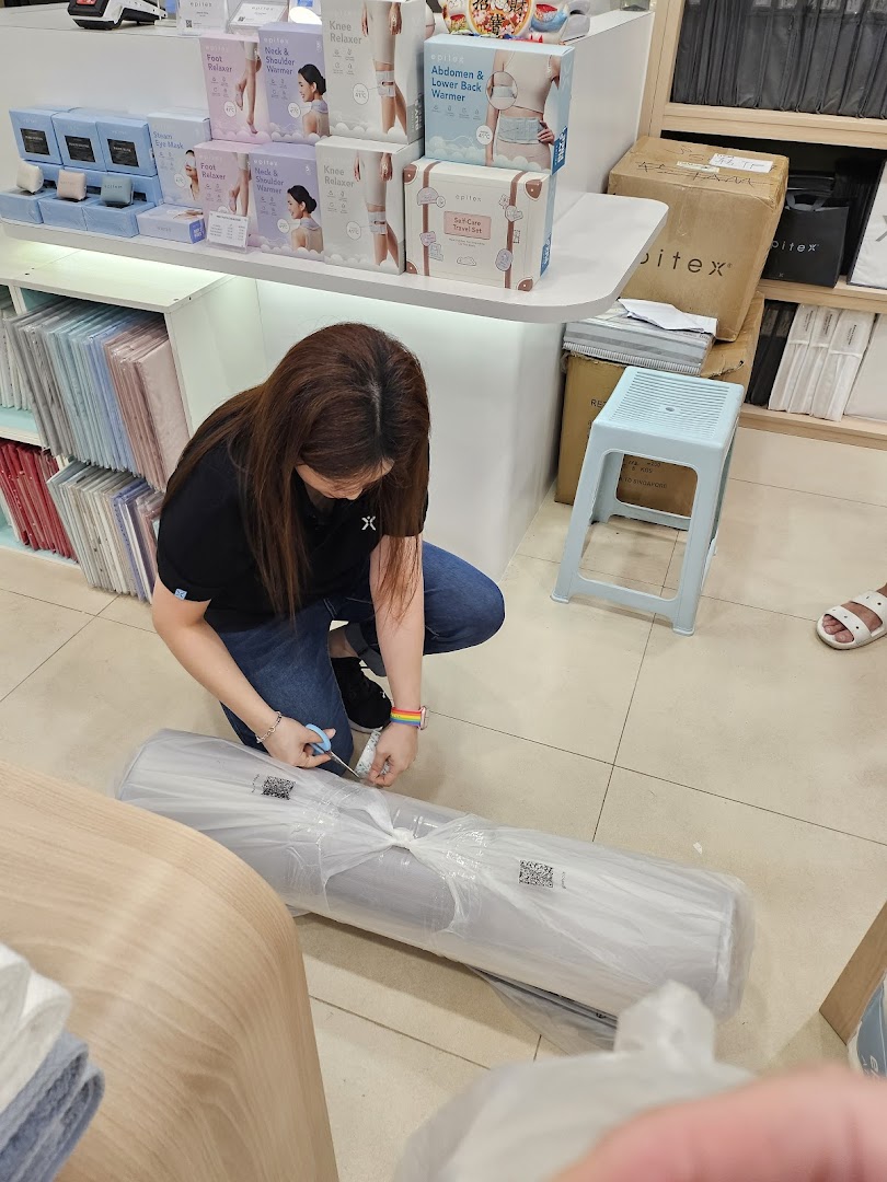 A staff member unboxes a large item inside the Epitex store, surrounded by various wellness products.