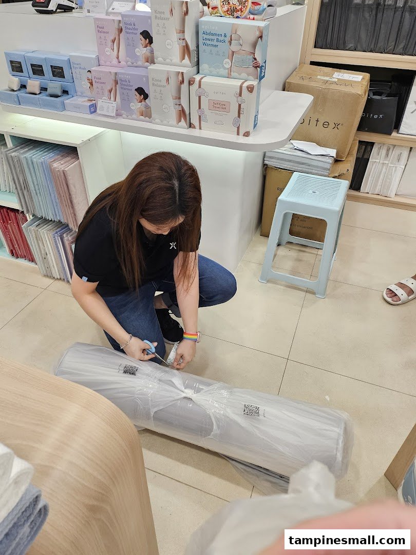 A staff member unboxes a large item inside the Epitex store, surrounded by various wellness products.