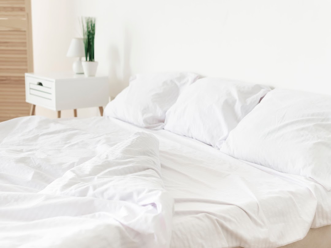 A clean, bright bedroom scene featuring a bed with crisp white bedding and pillows.