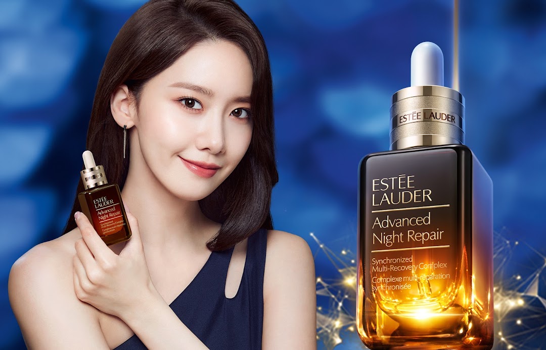 A model holding Estée Lauder Advanced Night Repair serum, with a larger product bottle displayed.