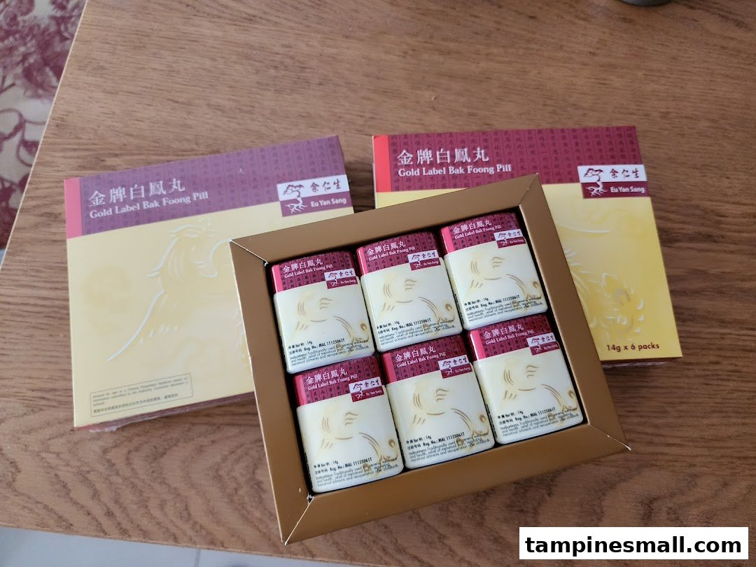 Boxes of Eu Yan Sang Gold Label Bak Foong Pill displayed on a wooden surface.