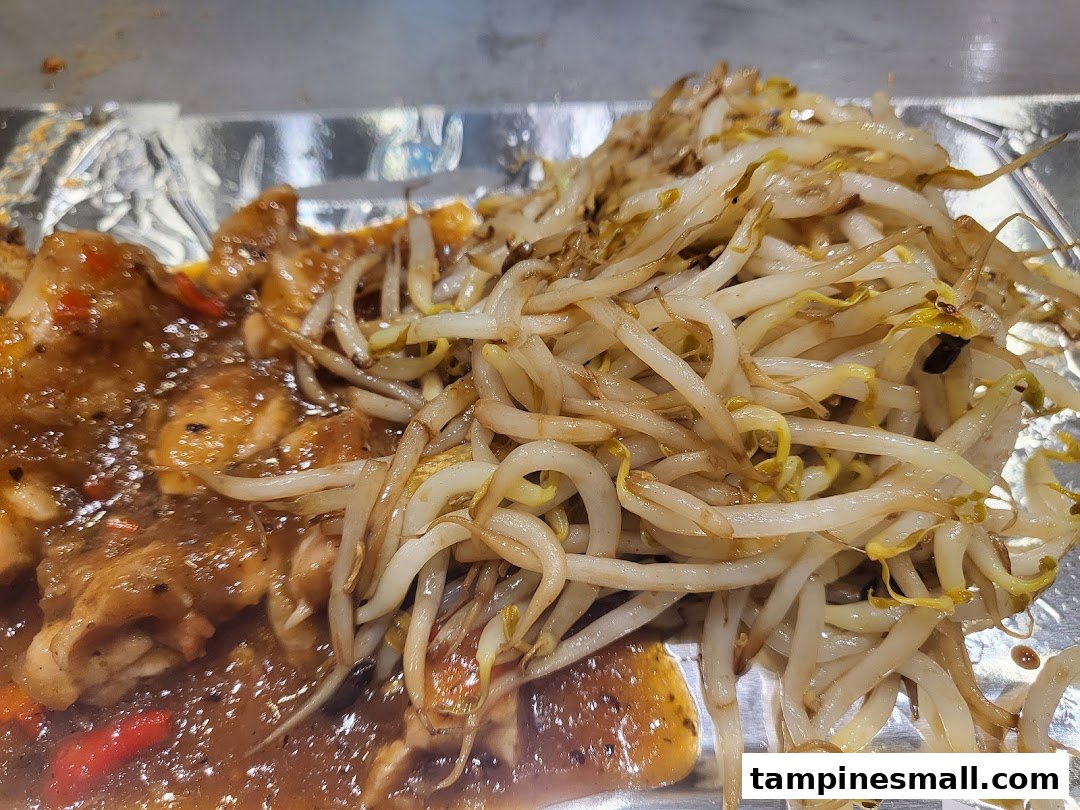 A close-up of savory teppanyaki chicken with vibrant stir-fried bean sprouts.