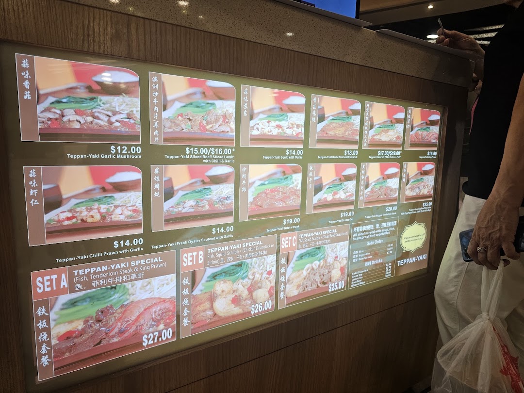 A digital menu board displaying various Teppan-Yaki dishes with prices and images.