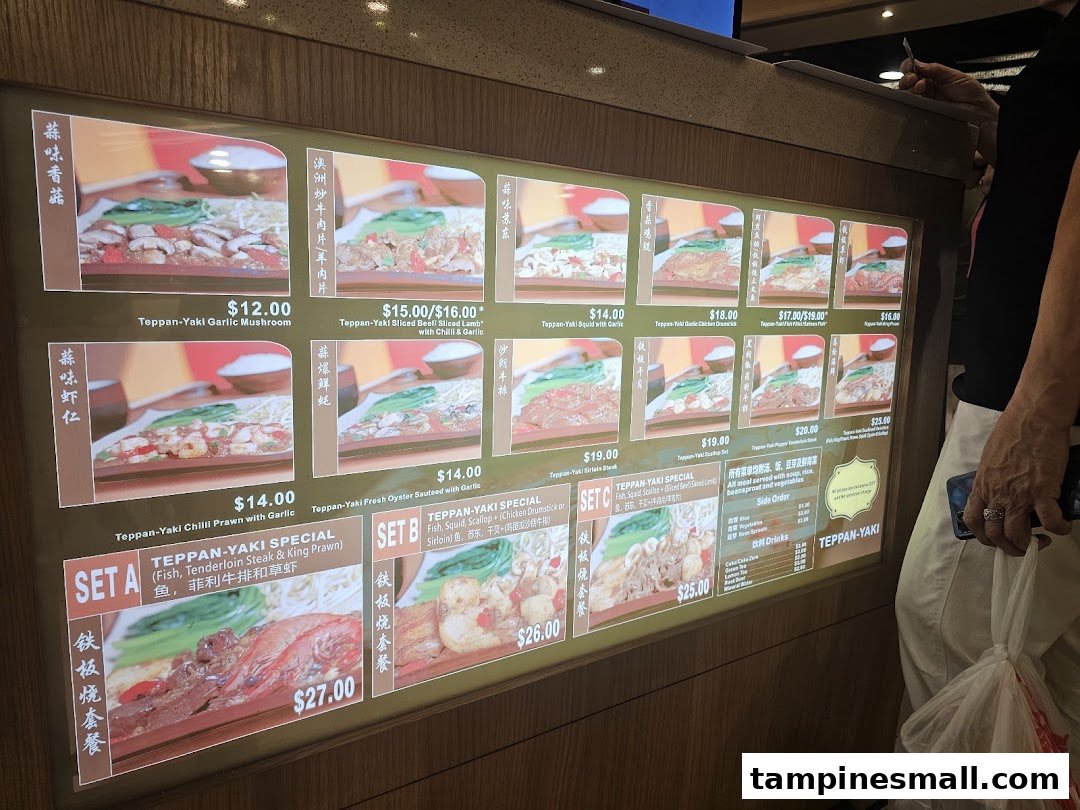 A digital menu board displaying various Teppan-Yaki dishes with prices and images.