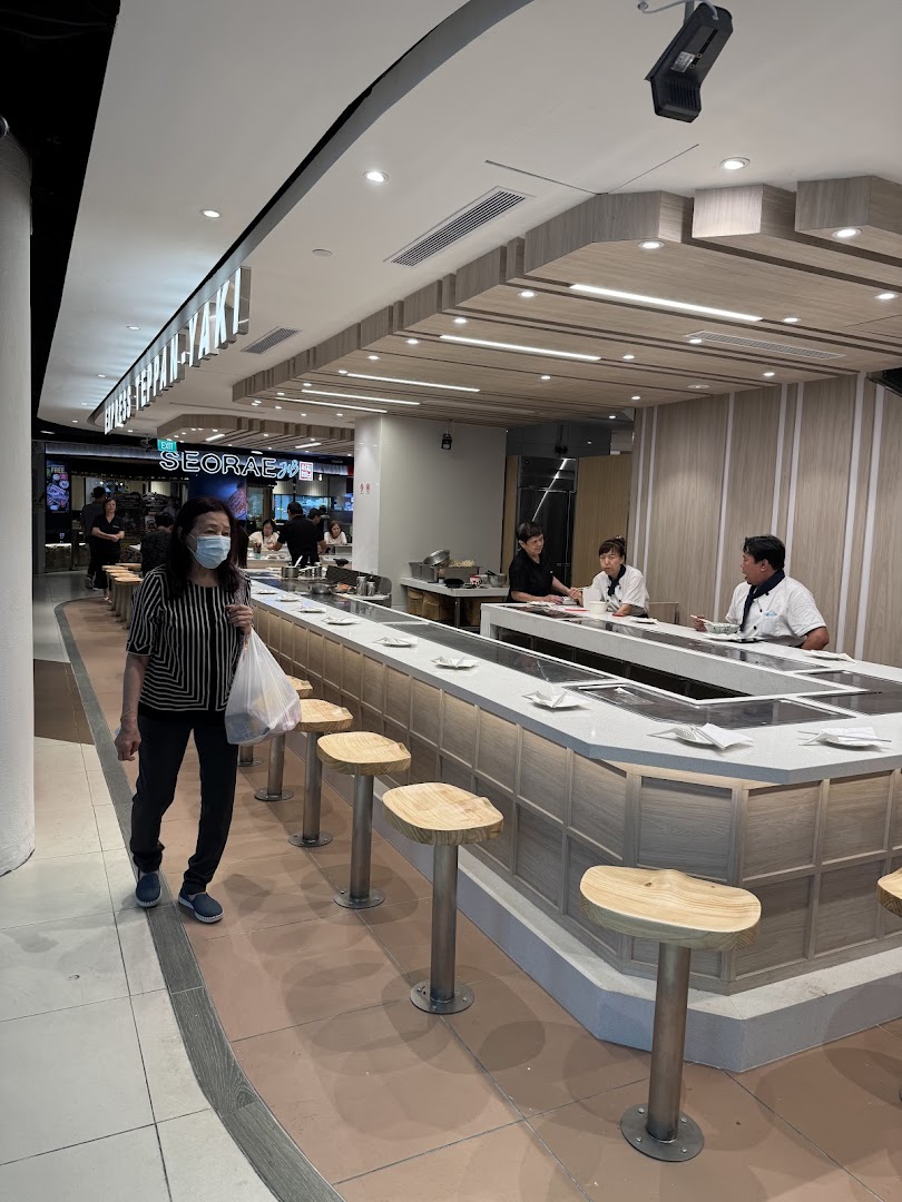 Diners seated at a modern teppanyaki counter with chefs preparing food at Express Teppan-Yaki.