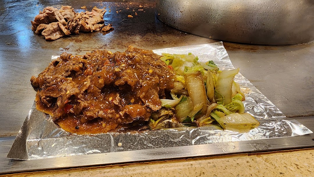 Sizzling teppanyaki beef with vegetables served fresh off the grill on a hot plate.