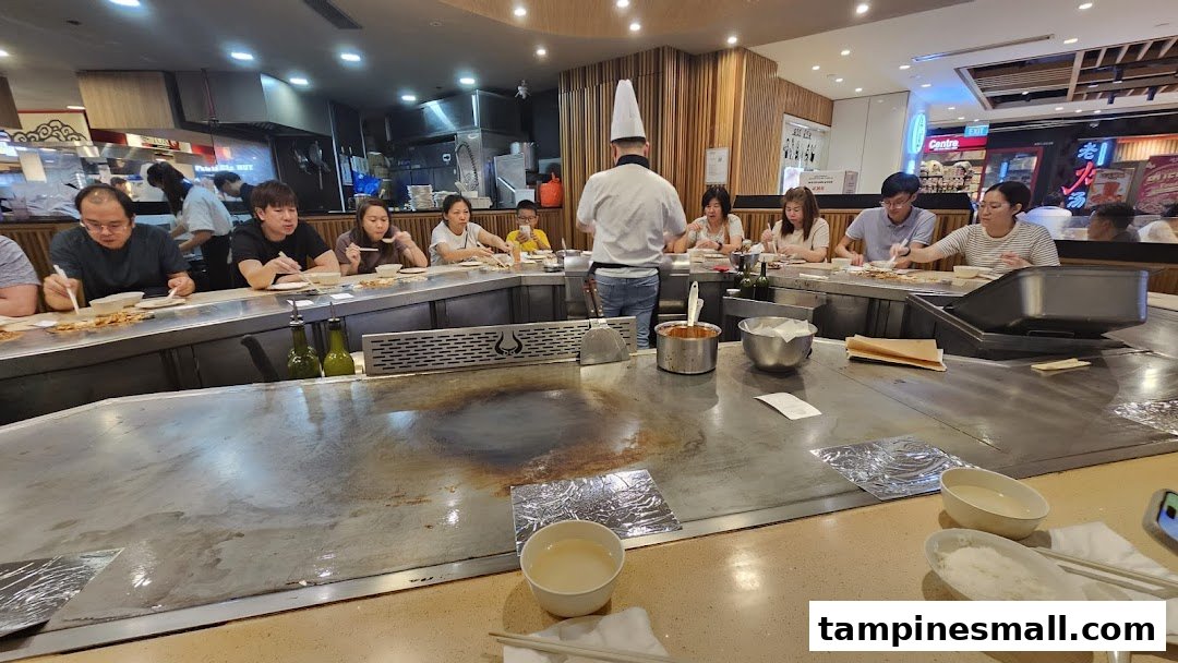 Diners enjoy a lively teppanyaki experience with a chef cooking fresh ingredients on a large grill.