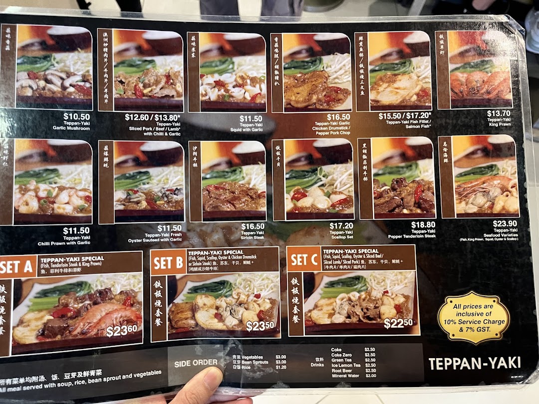 A detailed menu board displaying various Teppan-Yaki dishes, special sets, side orders, and drinks with prices.