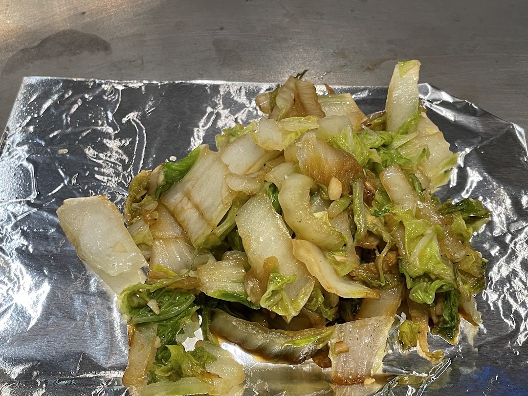 Close-up of stir-fried cabbage served on aluminum foil, likely from a teppan-yaki grill.