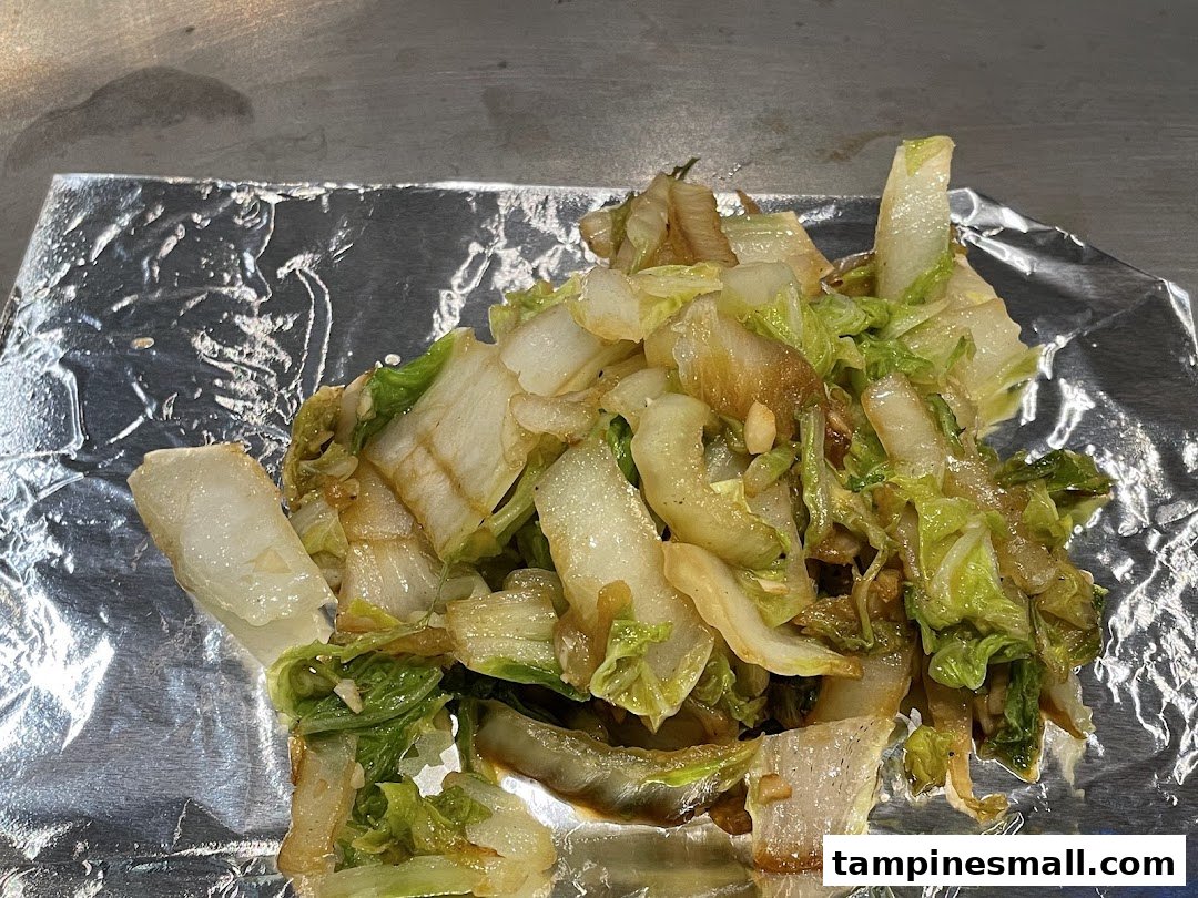 Close-up of stir-fried cabbage served on aluminum foil, likely from a teppan-yaki grill.