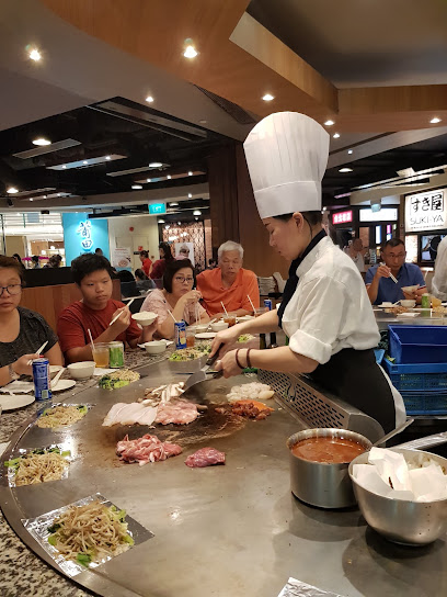 A chef prepares fresh ingredients on a teppanyaki grill for customers at Express Teppan-Yaki.