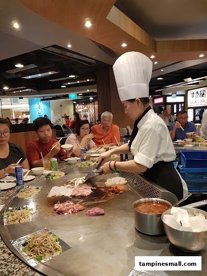 A chef prepares fresh ingredients on a teppanyaki grill for customers at Express Teppan-Yaki.