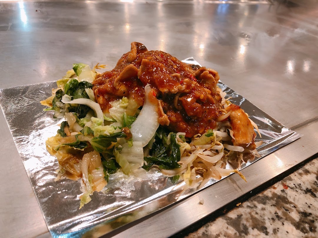A vibrant teppanyaki dish featuring sauced meat and fresh vegetables served on foil.