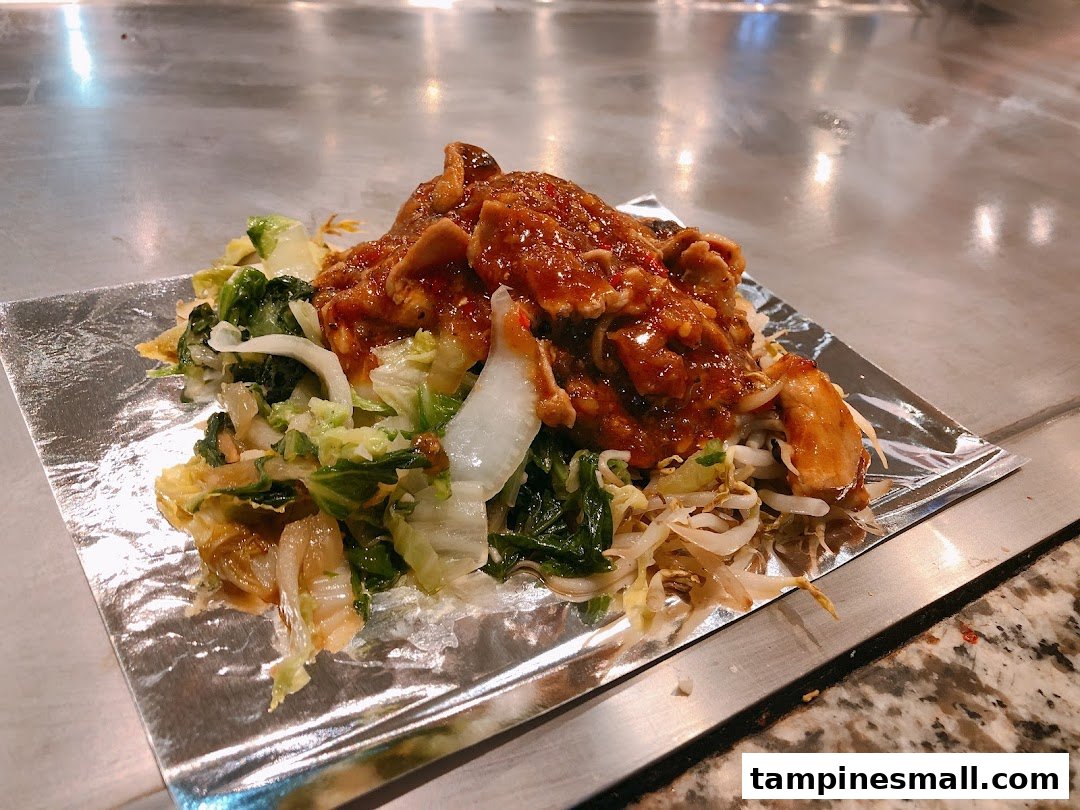 A vibrant teppanyaki dish featuring sauced meat and fresh vegetables served on foil.