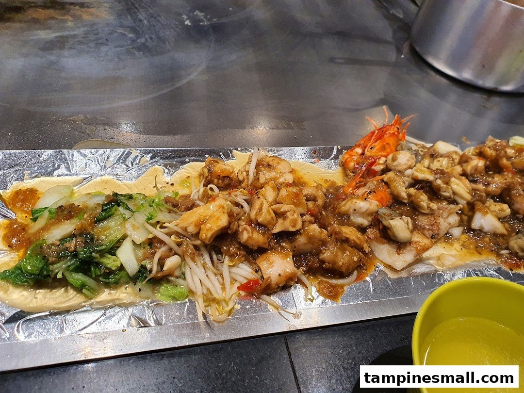 Assorted teppanyaki dishes, including vegetables, chicken, and seafood, cooking on a hot grill.