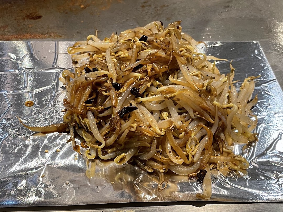 Close-up of stir-fried bean sprouts served on foil, fresh from a teppanyaki grill.