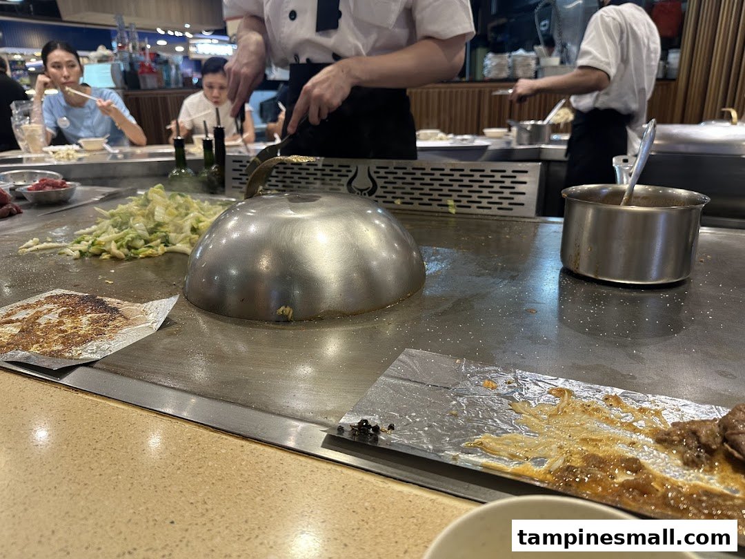 A chef cooks teppanyaki dishes on a hot griddle for customers at Express Teppan-Yaki.